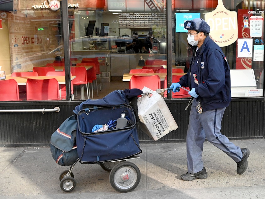 caption: A mail carrier makes deliveries in New York City on March 14. USPS says gloves and surgical masks are made available to all employees who request them, but many postal workers say they don't have what they need.