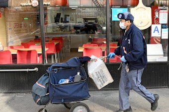 caption: A mail carrier makes deliveries in New York City on March 14. USPS says gloves and surgical masks are made available to all employees who request them, but many postal workers say they don't have what they need.