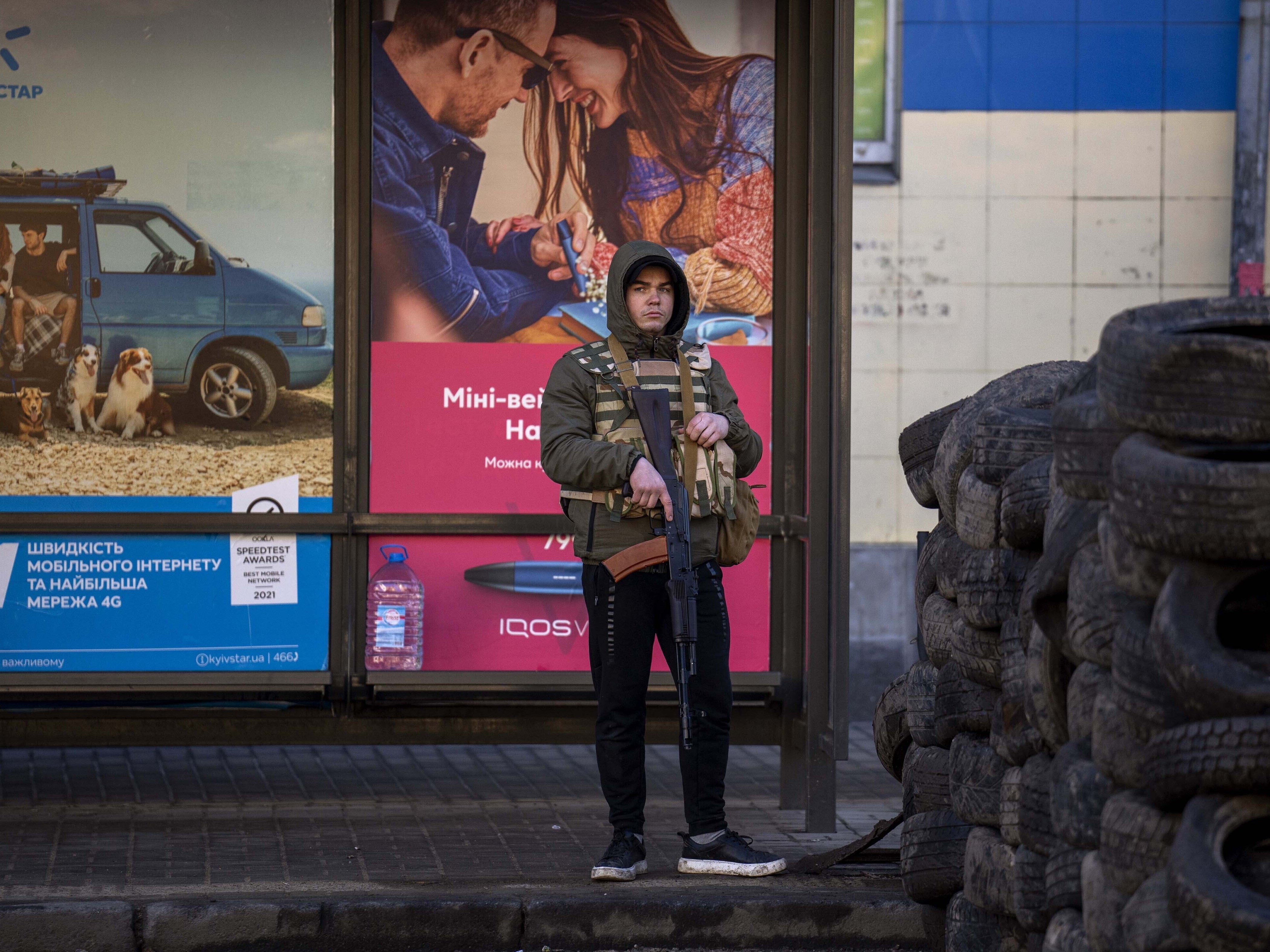 caption: A civil defense guard stands at a checkpoint in Kyiv, Ukraine, on Saturday. Russian troops stormed toward Ukraine's capital, and street fighting broke out as city officials urged residents to take shelter.