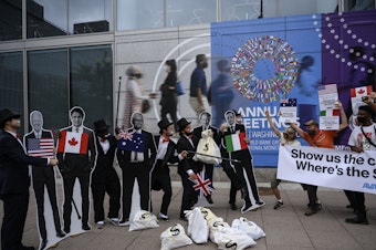 caption: Activists dressed as debt collectors hold cutouts of the leaders of the United States, Canada, Australia, the UK and Italy in front of the International Monetary Fund headquarters in Washington, D.C., last month to ask rich nations to keep their financial commitment to developing countries to tackle climate change.