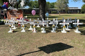 caption: A memorial to the students and faculty who died stands in front of Robb Elementary School in Uvalde, Texas. It's not clear who put the memorial up and authorities have not released the names of the deceased.