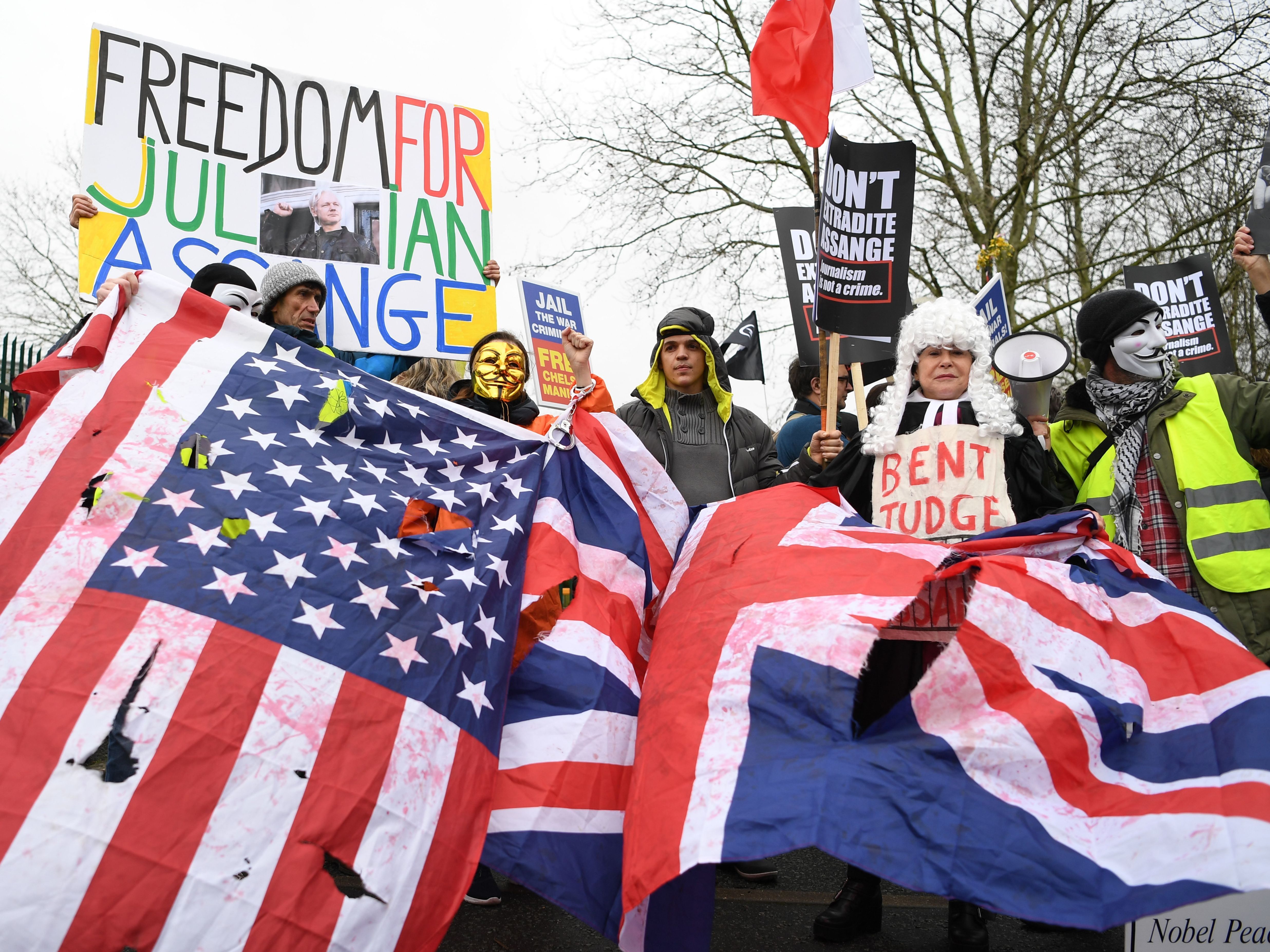 caption: Supporters of WikiLeaks co-founder Julian Assange hold U.S. and U.K. flags outside Woolwich Crown Court in southeast London on Monday as his extradition hearing begins.