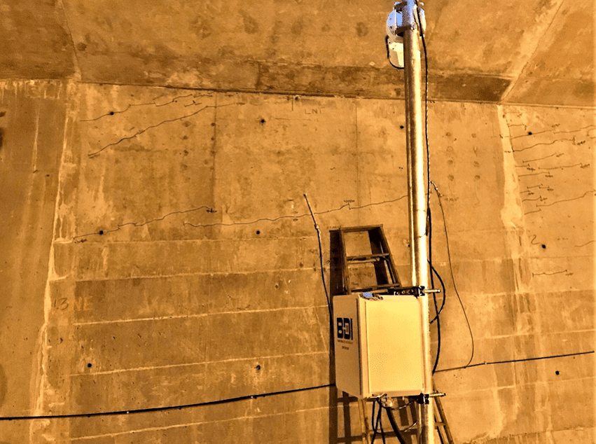 caption: A monitoring device beneath the low-rise Spokane Street bridge measures its cracks every 20 seconds.
