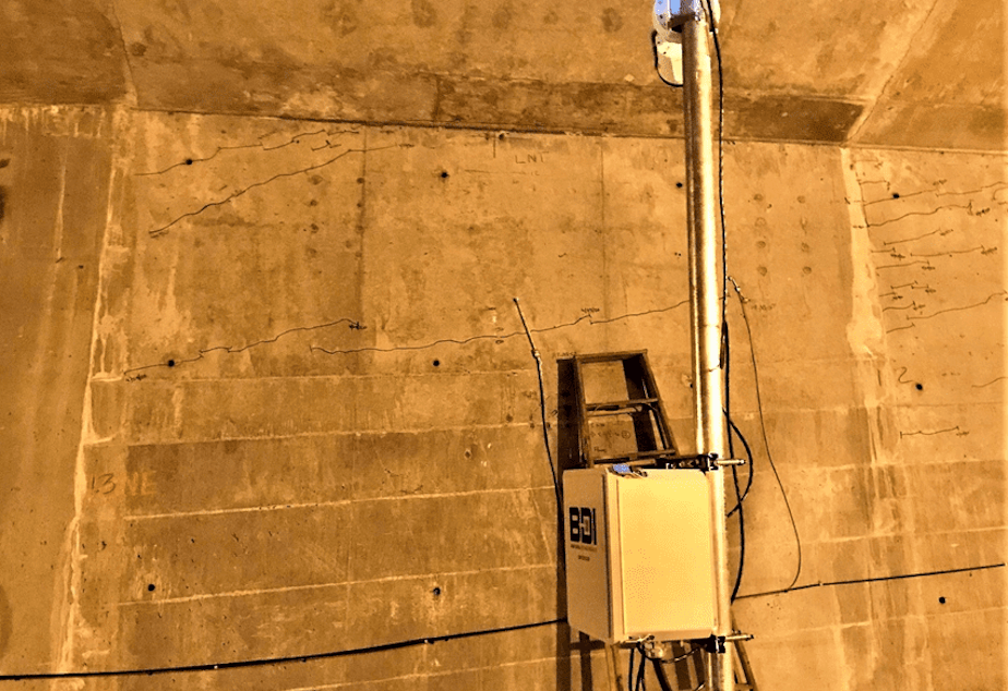 caption: A monitoring device beneath the low-rise Spokane Street bridge measures its cracks every 20 seconds.
