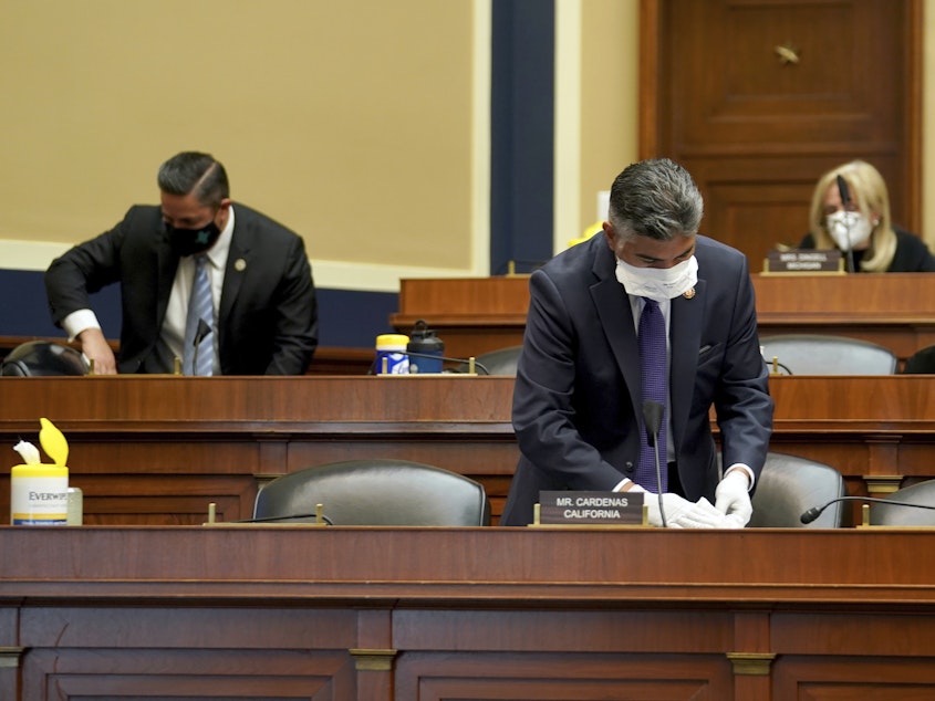 caption: Rep. Tony Cardenas, D-Calif., cleans his desk during a House Energy and Commerce Subcommittee on Health hearing earlier this month.