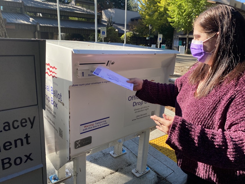 caption: Violet, who didn't want to give her last name, drops her ballot in a drop box at Lacey City Hall in Thurston County on Monday.