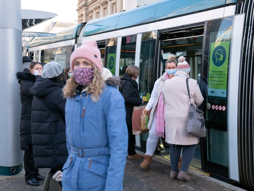 caption: People step off a tram in Nottingham, England, a city where a case of the omicron variant of the coronavirus was identified last week.