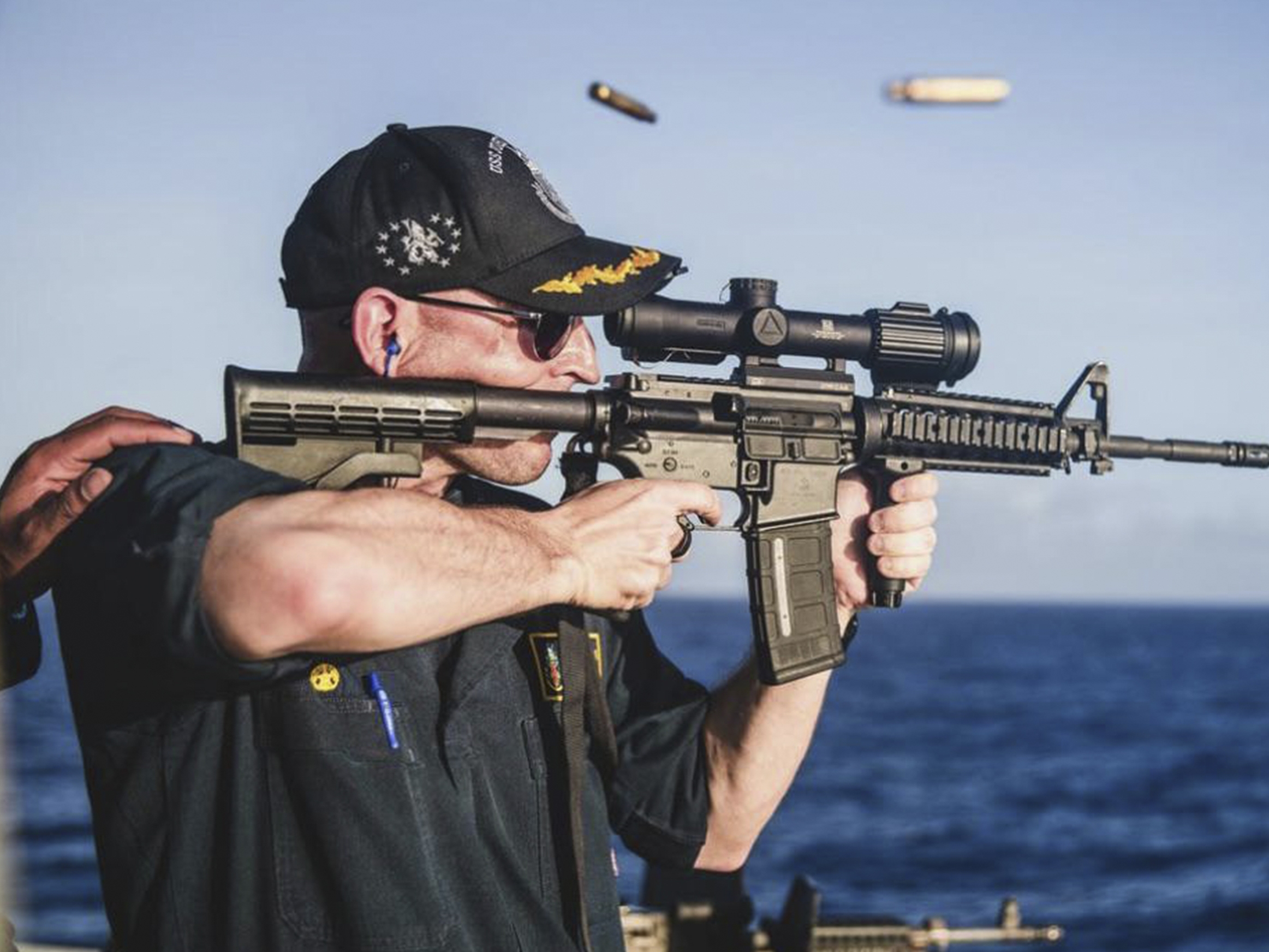 caption: This undated photo, provided by <em>Stars and Stripes</em>, shows Cameron Yaste, commanding officer of the destroyer USS John McCain, firing a rifle with a backwards scope.