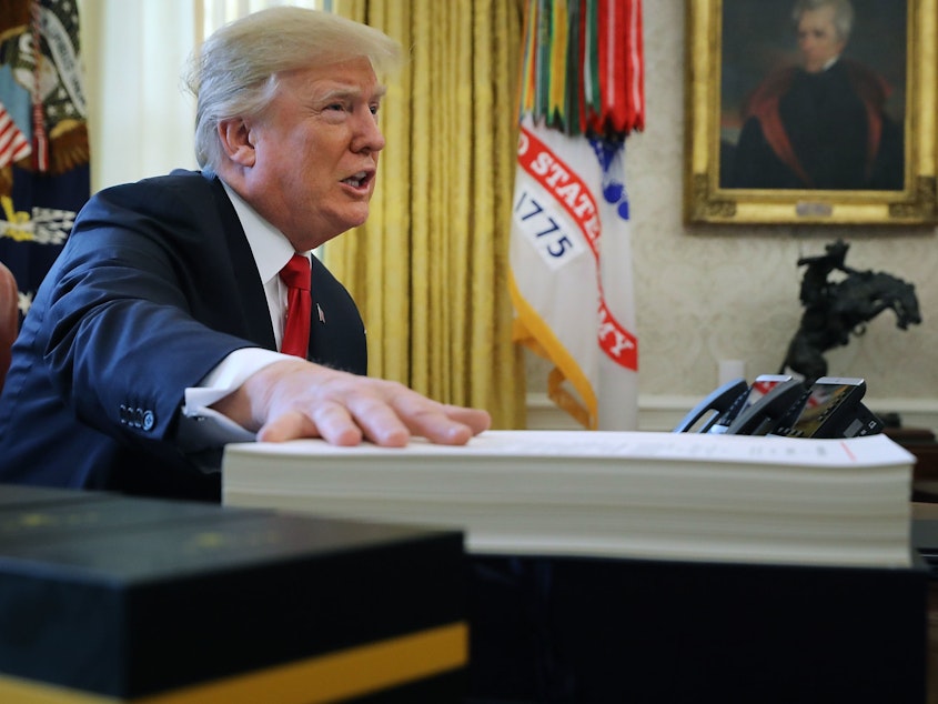 caption: Analysts say real estate tax breaks allowed President Trump to personally avoid high taxes. Above, Trump prepares to sign tax legislation into law in the Oval Office on Dec. 22, 2017.