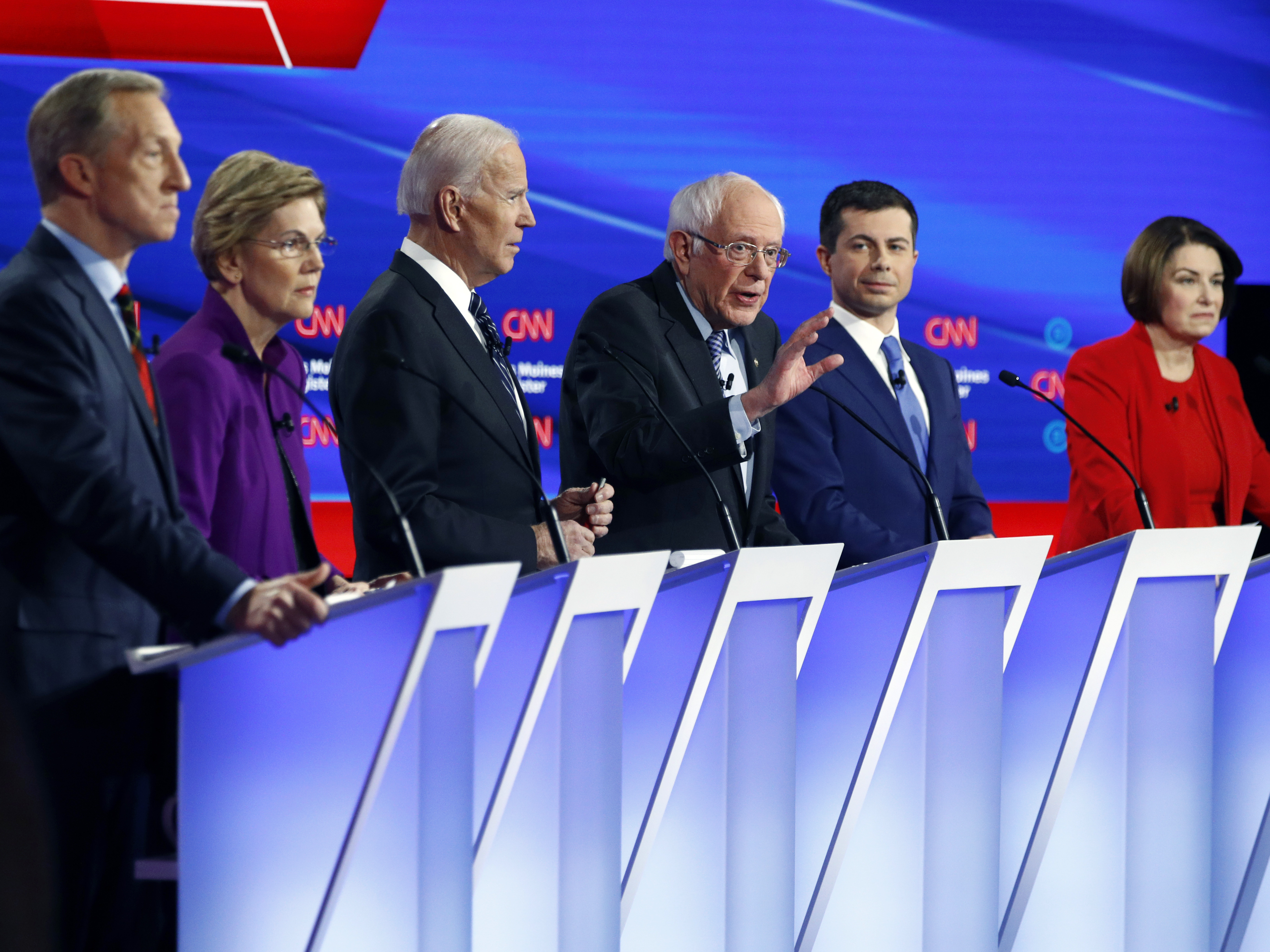 caption: Democratic presidential candidate Sen. Bernie Sanders, center, speaks as fellow candidates businessman Tom Steyer, from left, Sen. Elizabeth Warren, former Vice President Joe Biden, former South Bend Mayor Pete Buttigieg and Sen. Amy Klobuchar, listen on Jan. 14, during a Democratic presidential debate hosted by CNN and <em>The Des Moines Register</em>.