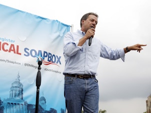 caption: Montana Gov. Steve Bullock speaks at the Des Moines Register Soapbox during a visit to the Iowa State Fair in August 2018.
