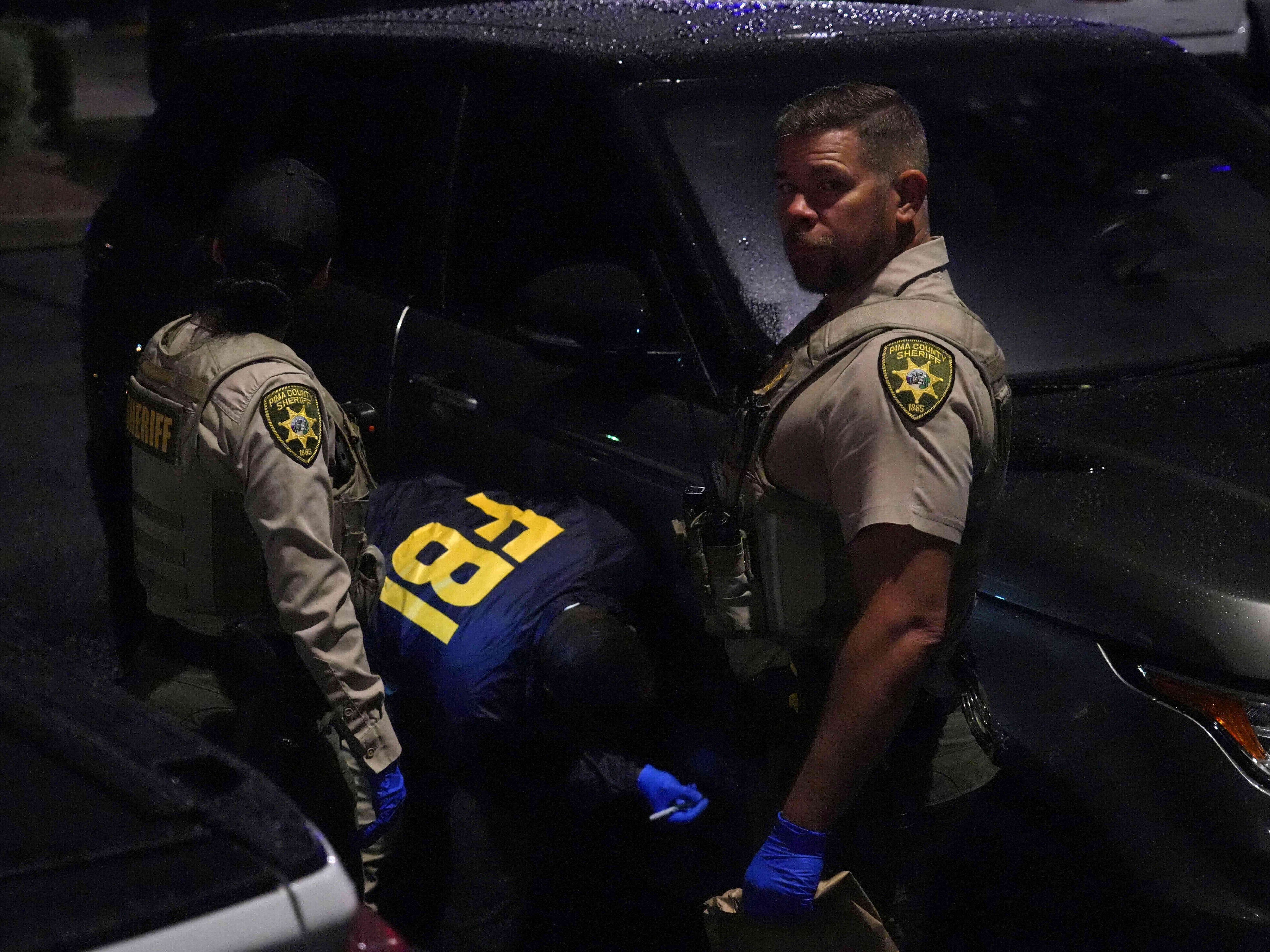 caption: Law enforcement from the Pima County Sheriff's Department and the FBI work on a Range Rover in a Culver's parking lot in Tucson, Ariz., early Saturday.