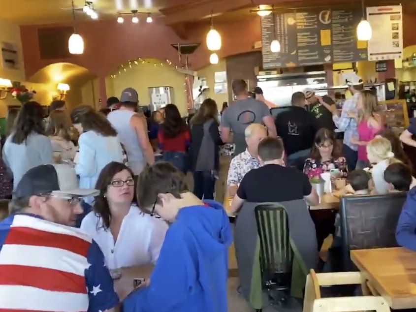 caption: A large crowd of people are seen at C&C Coffee and Kitchen in Castle Rock, Colo., celebrating Mother's Day as the restaurant opened its dining room in defiance of state orders.
