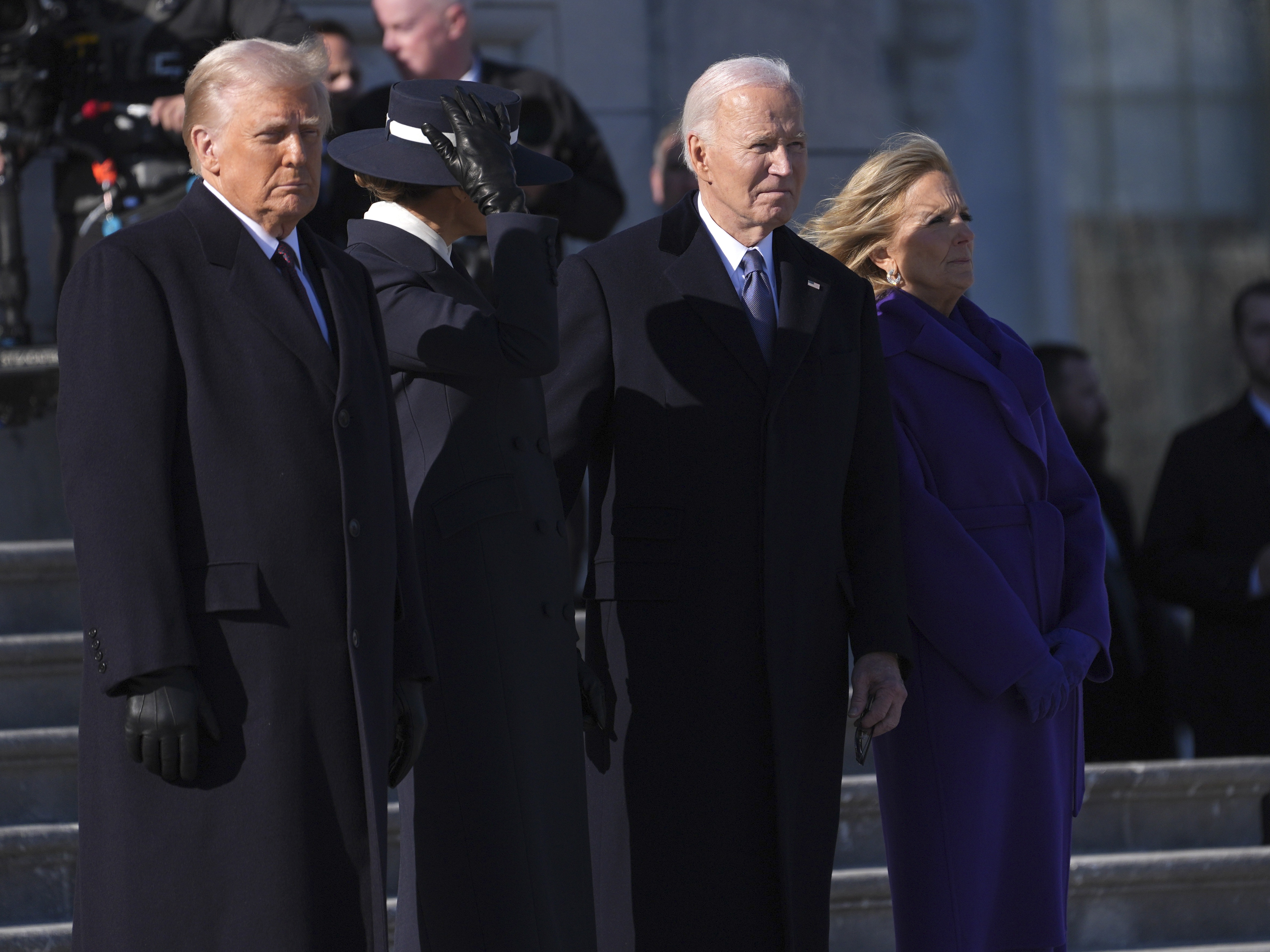 caption: President Trump and first lady Melania Trump stand before sending off former President Joe Biden and Jill Biden to board a Marine helicopter en route to Joint Base Andrews after the inauguration on Jan. 20, at the U.S. Capitol in Washington.