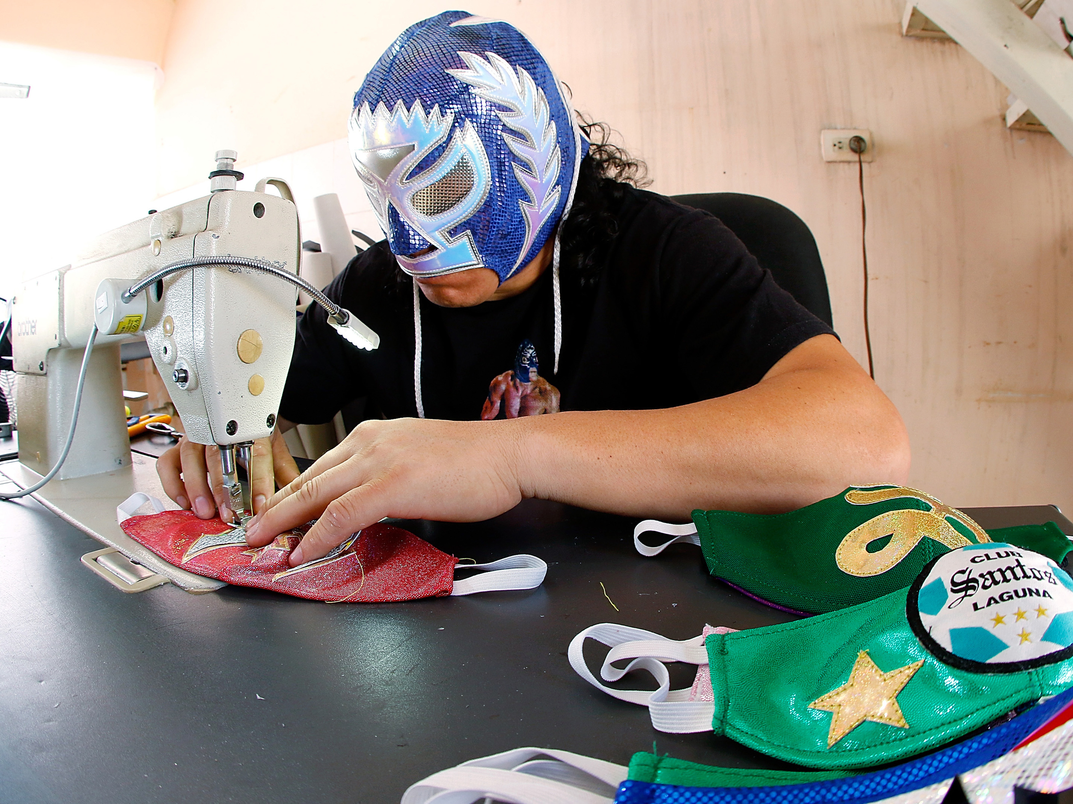 caption: Mexican <em>lucha libre</em> wrestler Hijo del Soberano sews face masks since his matches have stopped due to the COVID-19 pandemic.