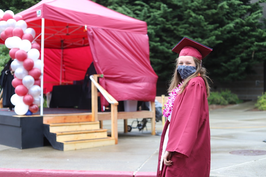 caption: Graduating senior Hailey Vandenbosch smiles as she waits for her name to be announced, before walking onto the makeshift stage to receive her diploma sleeve on June 9, 2020. Given the “circumstances and the short amount of time…to plan the ceremony,” Vandenbosch thought the drive-through graduation was “‘much more personalized” than normal.