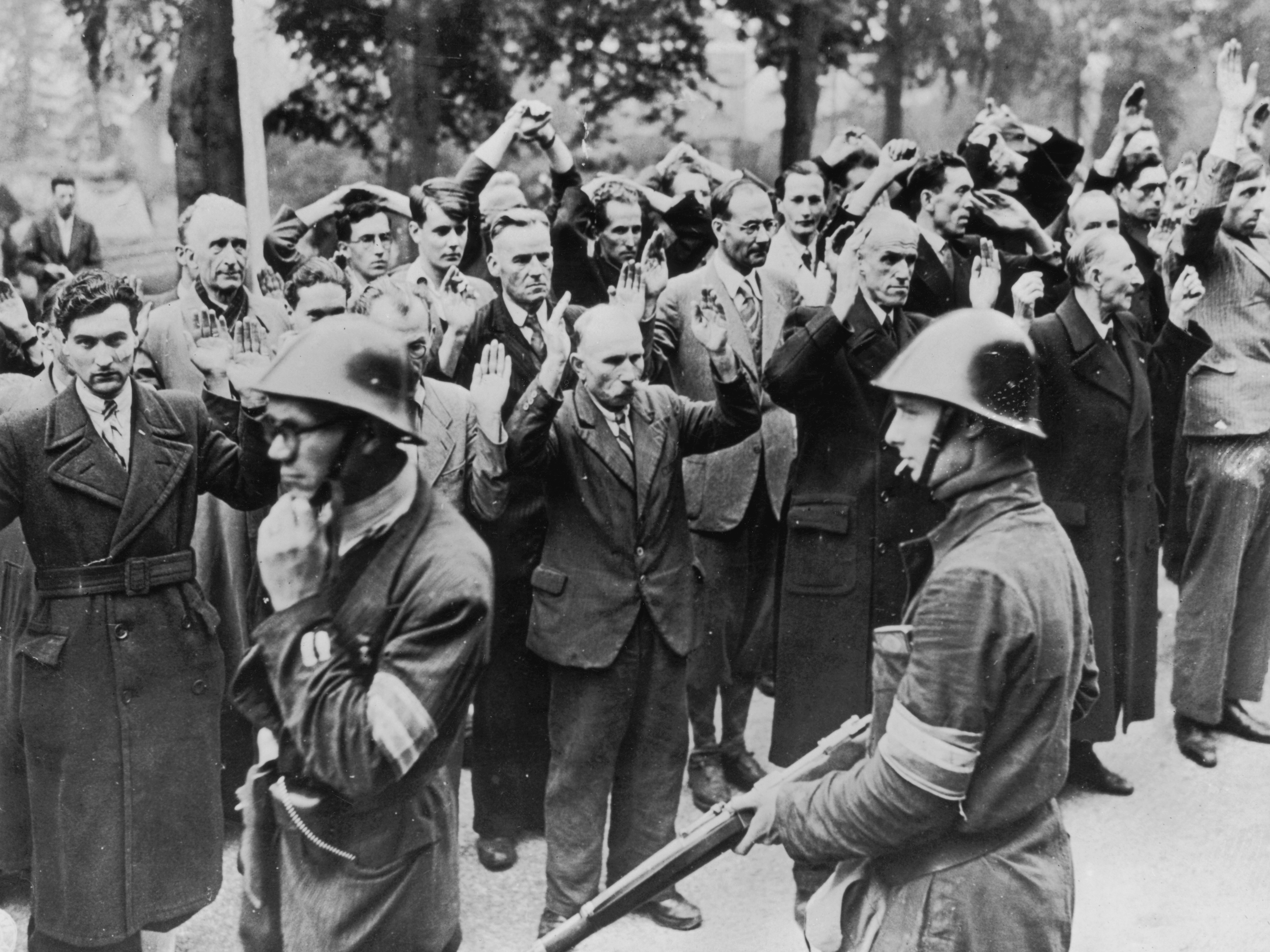 caption: Armed Dutch patriots round up fellow townspeople accused of collaborating with the Nazis in Nijmegen in October 1944.