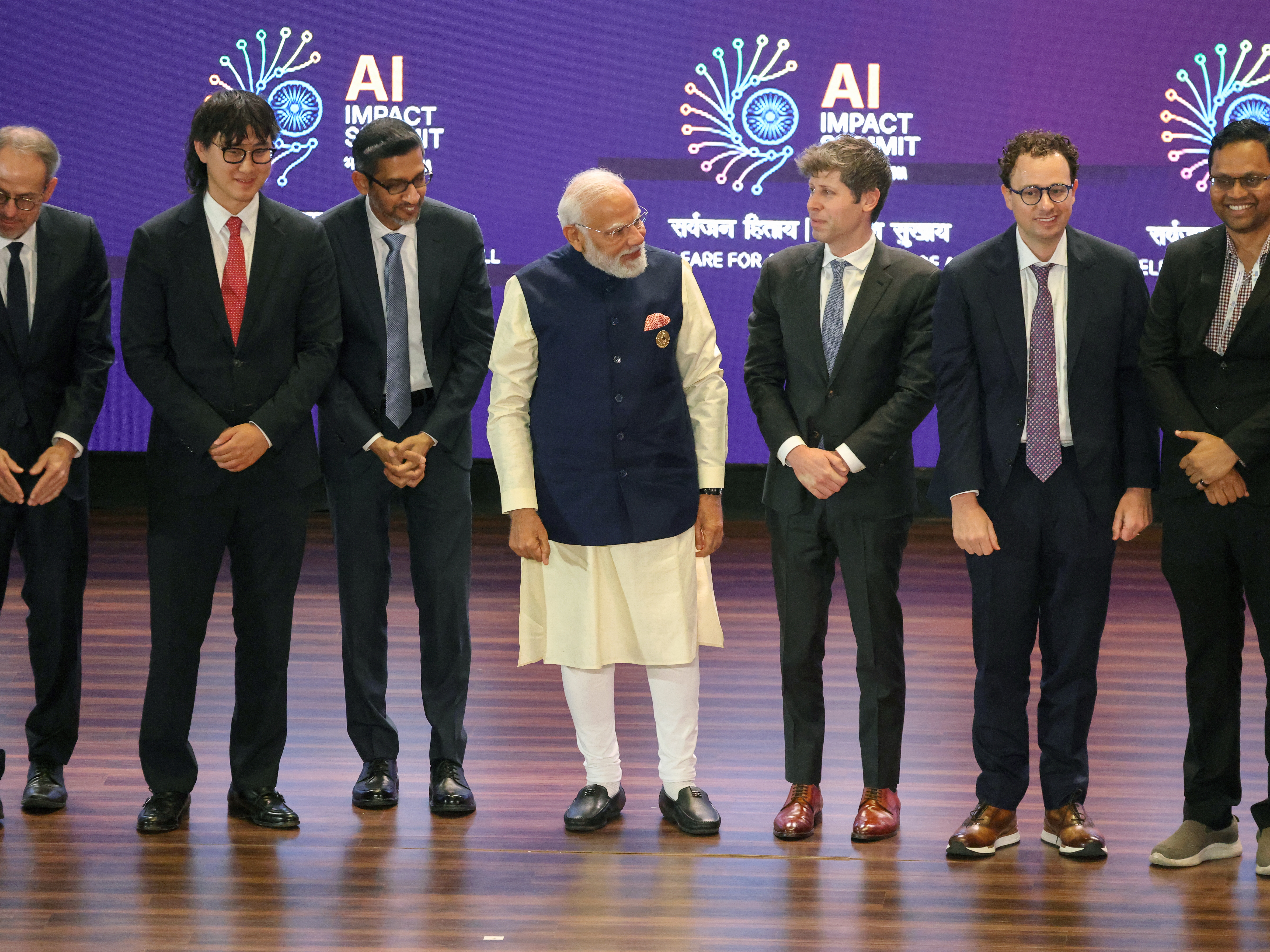 caption: Indian Prime Minister Narendra Modi (center) takes a group photo with AI company leaders, including OpenAI CEO Sam Altman (third from right), Anthropic CEO Dario Amodei (second from right), Google CEO Sundar Pichai (third from left) and Meta Chief AI Officer Alexandr Wang (second from left), at the AI Impact Summit in New Delhi on Feb. 19.