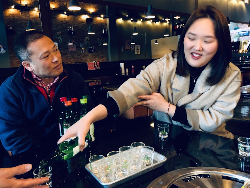 caption: The proper way to serve soju comes from traditional Korean culture. 