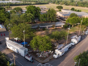 caption: An aerial view of Robb Elementary School and the makeshift memorial for the shooting victims in Uvalde.