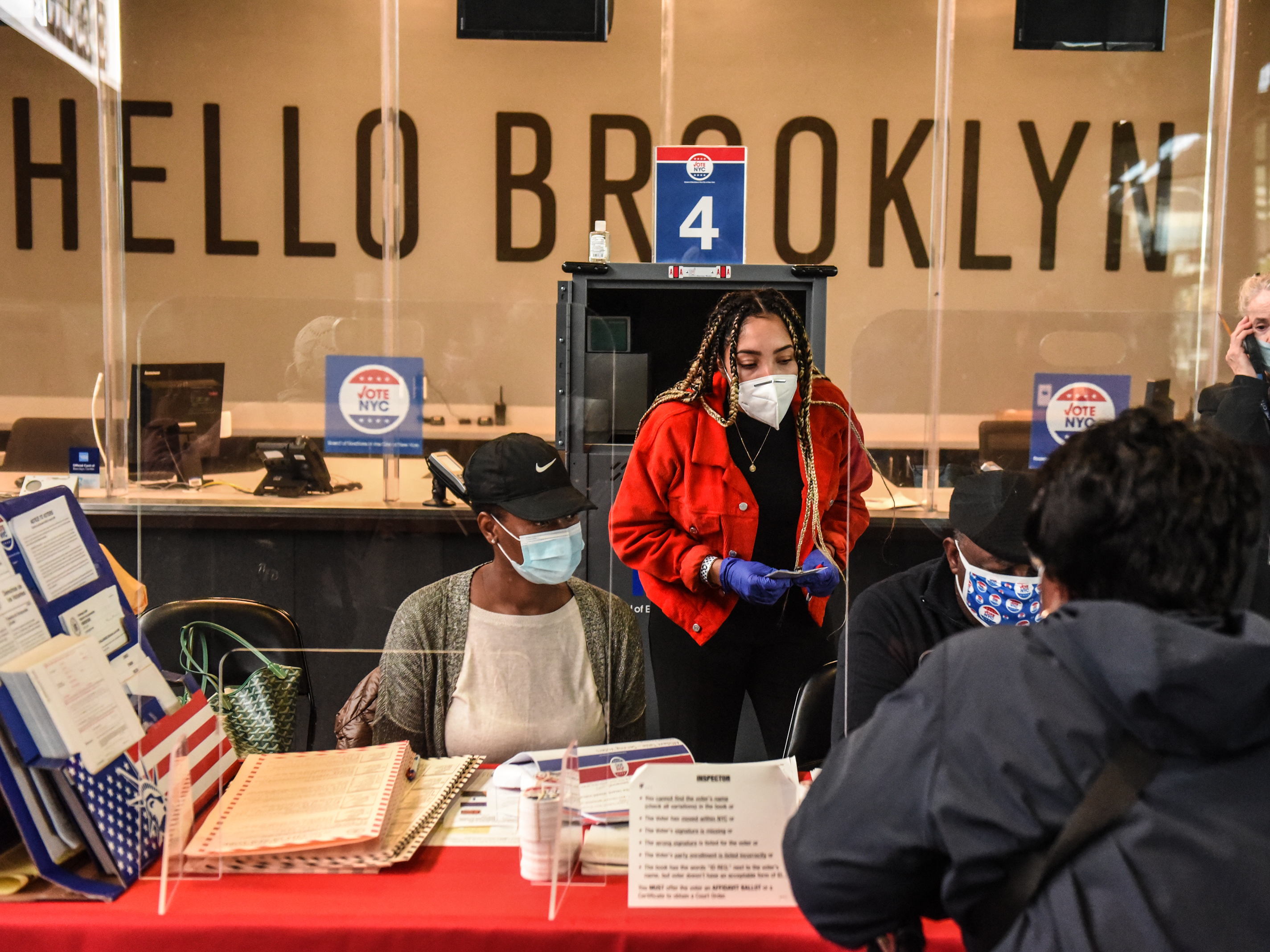 caption: Poll workers check in a voter at the Barclays Center in New York City on Oct. 24.