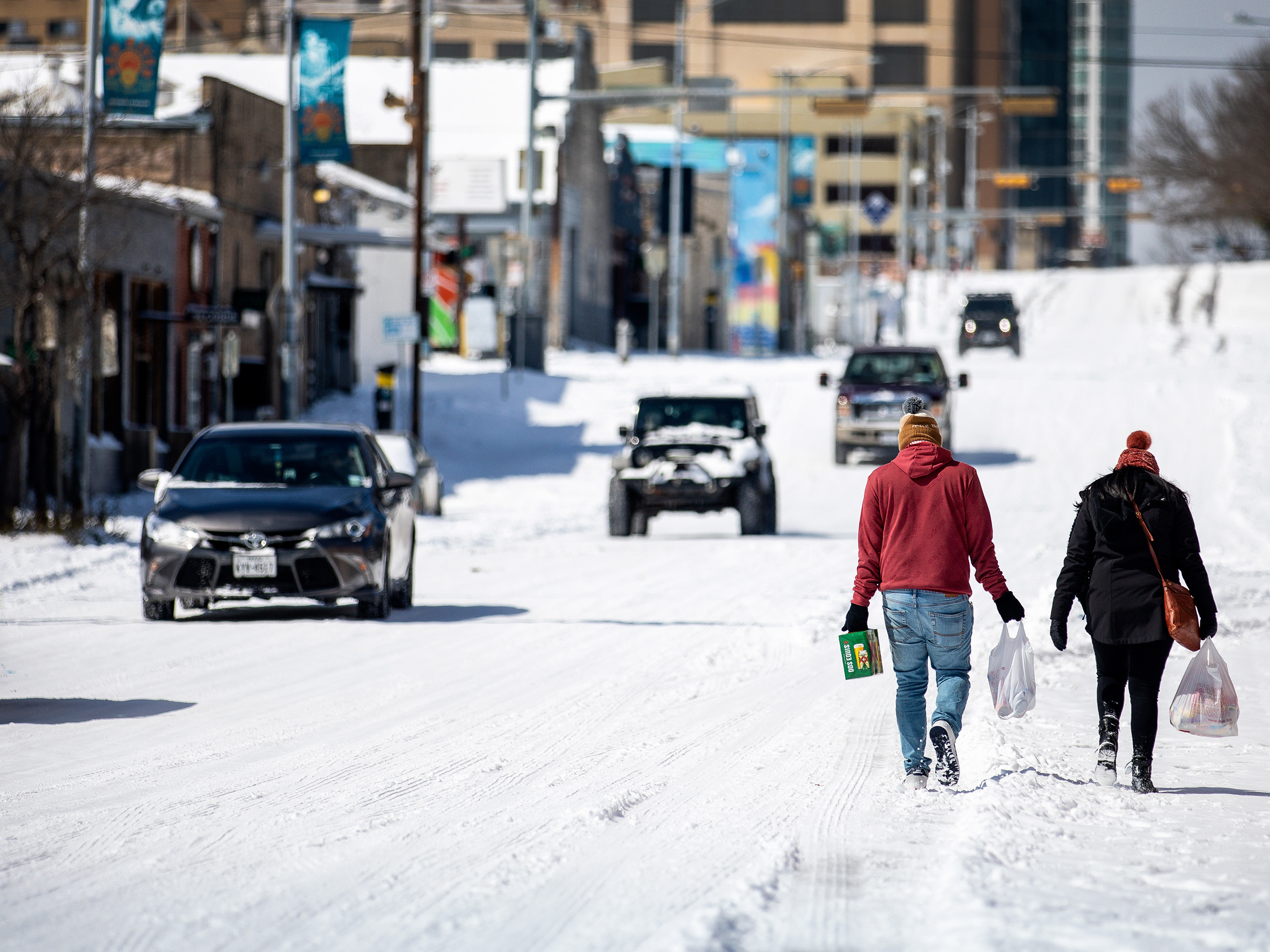caption: People carry groceries from a gas station on Monday in Austin, Texas. A winter storm has brought historic cold weather to the state, causing traffic delays and millions of customers to lose power.