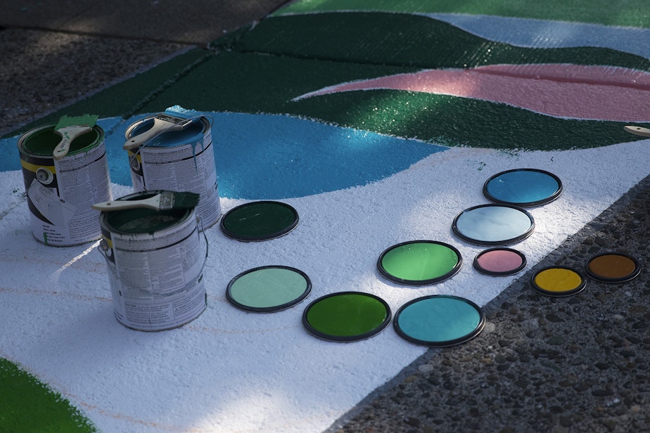 caption: The tops of paint cans are shown as the Black Lives Matter street mural is repainted by local artists on Friday, October 2, 2020, on E. Pine Street in Seattle.
