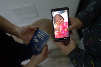 caption: Flavia holds a photo of her late daughter, Kayla, next to Evelin's new passport. They were having a weekend celebration of a relative's birthday on Jan. 28th.