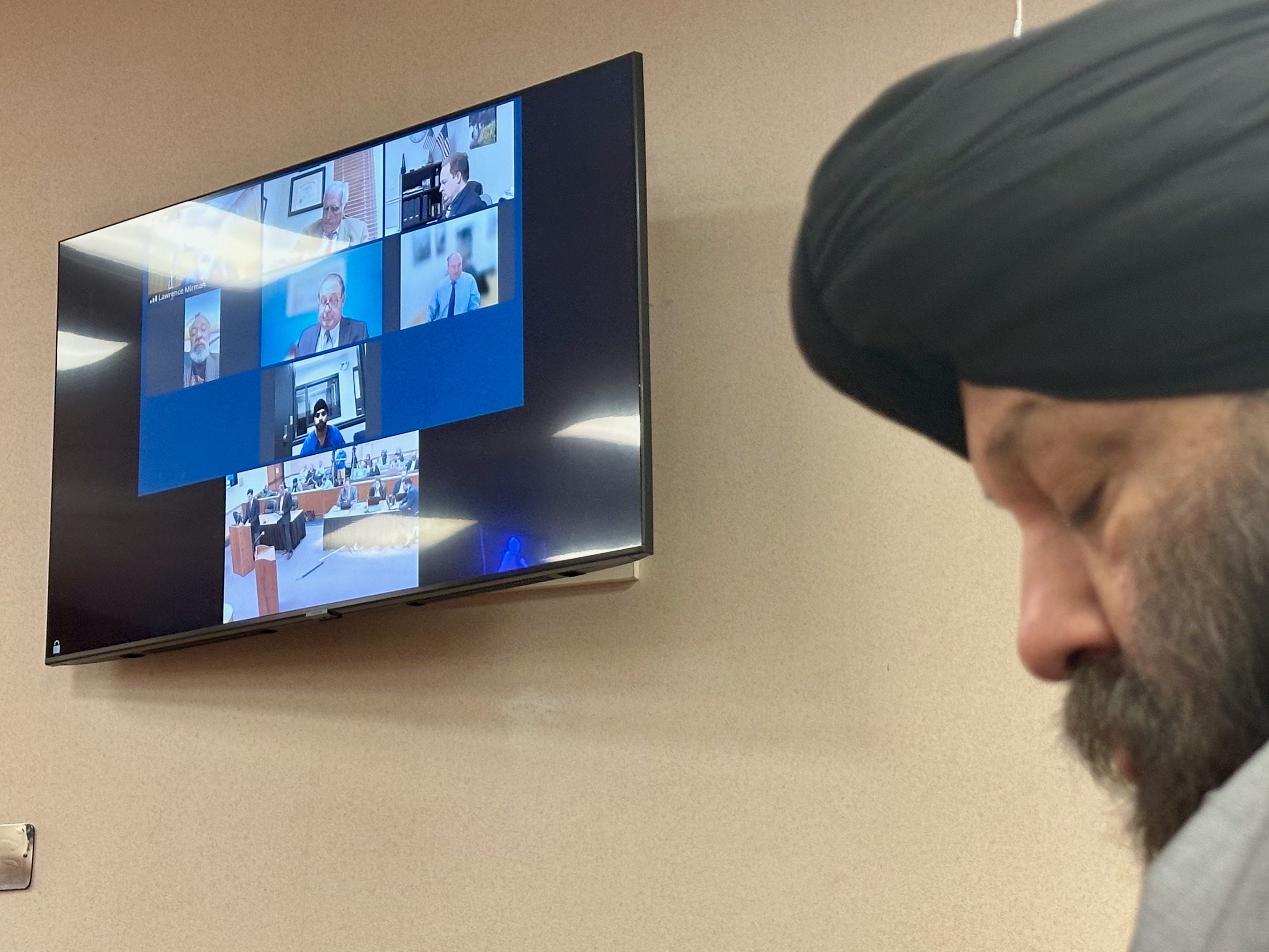 caption: Harjinder Singh is seen on a video screen next to his attorney Tejinder Bains during court proceedings in Fort Pierce, Fla. on Nov. 13, 2025. The Indian-born Singh was behind the wheel of an 18-wheeler in August when he allegedly made an illegal U-turn, causing a crash that killed three people.