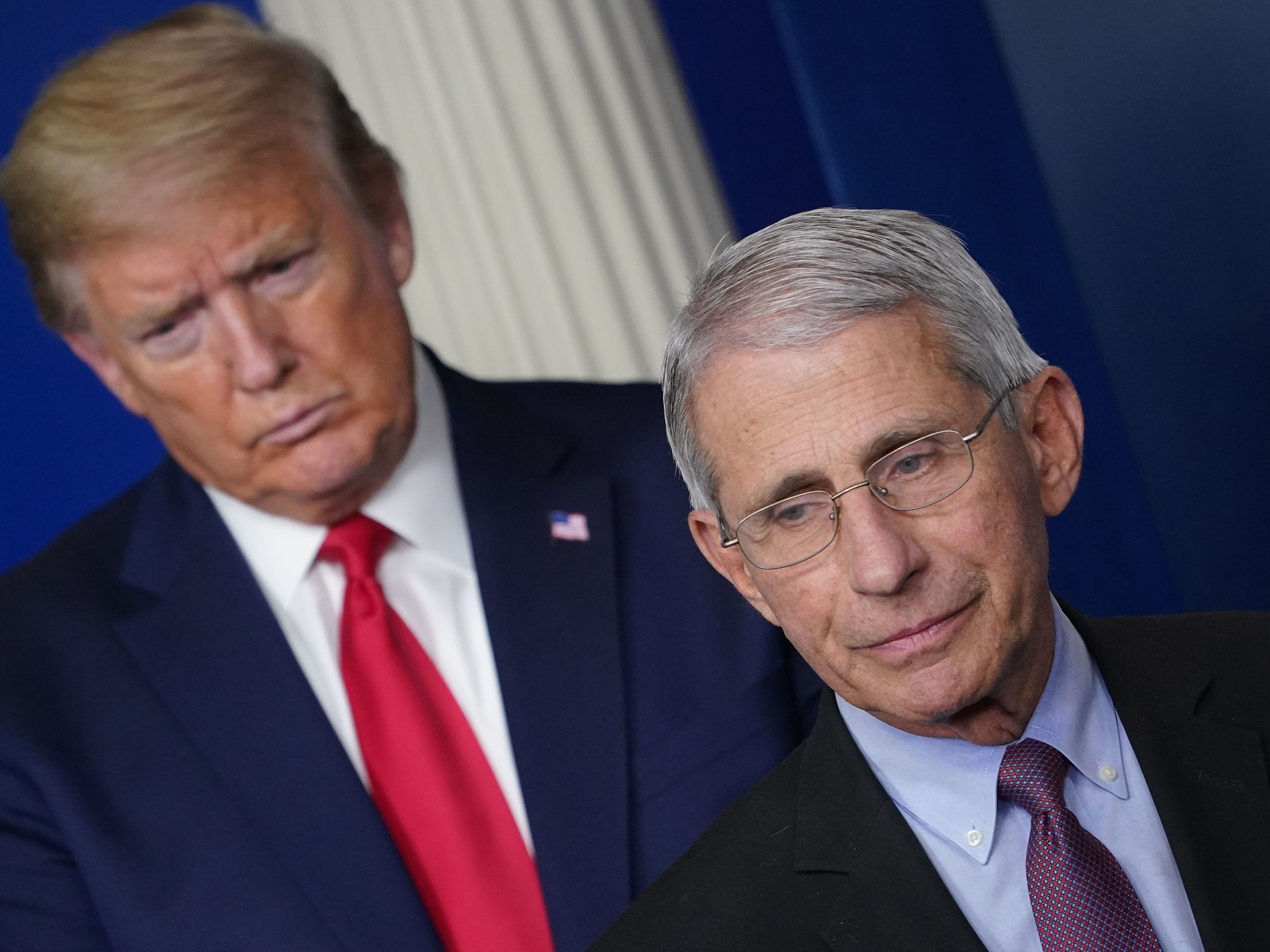 caption: Flanked by President Trump, Dr. Anthony Fauci speaks during a coronavirus task force briefing last month at the White House.