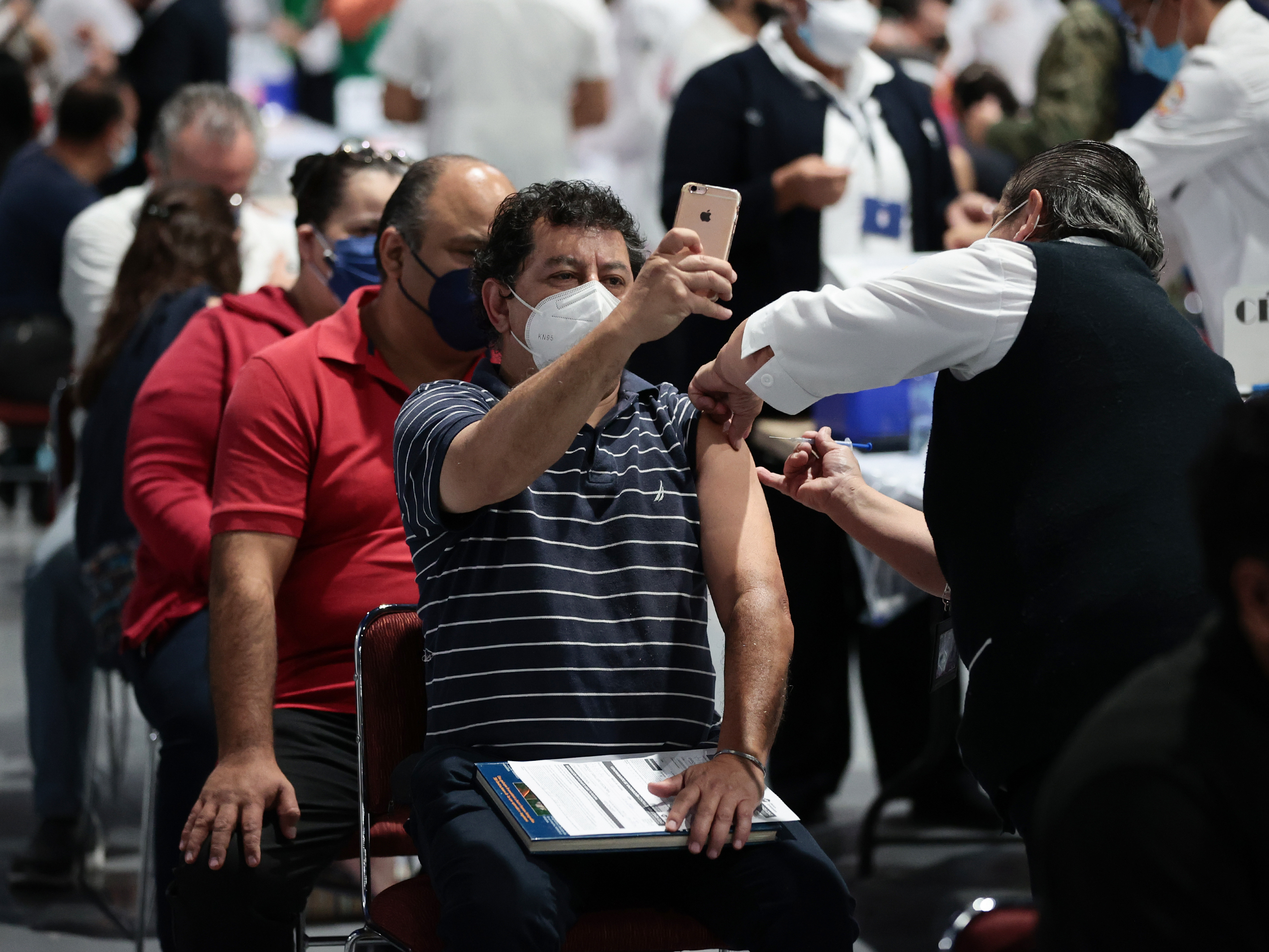caption: A man takes a selfie while getting the COVID-19 vaccine during a vaccination day in Mexico City.