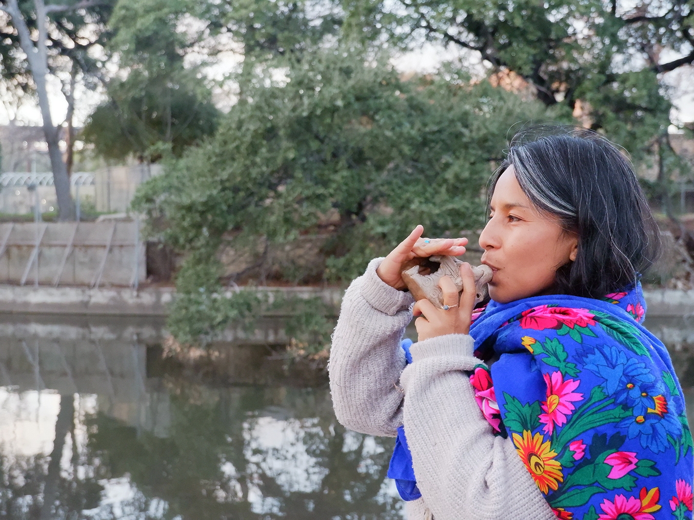 caption: Excy Guajardo blows a jaguar whistle, as a representation of the panther's roar in a Coahuiltecan creation story, along the San Antonio River.