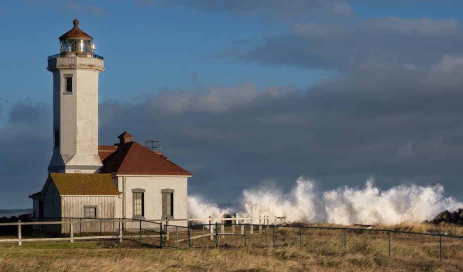 caption: Waves break at the Point Wilson Lighthouse in Port Townsend during a king tide on Dec. 8, 2021.