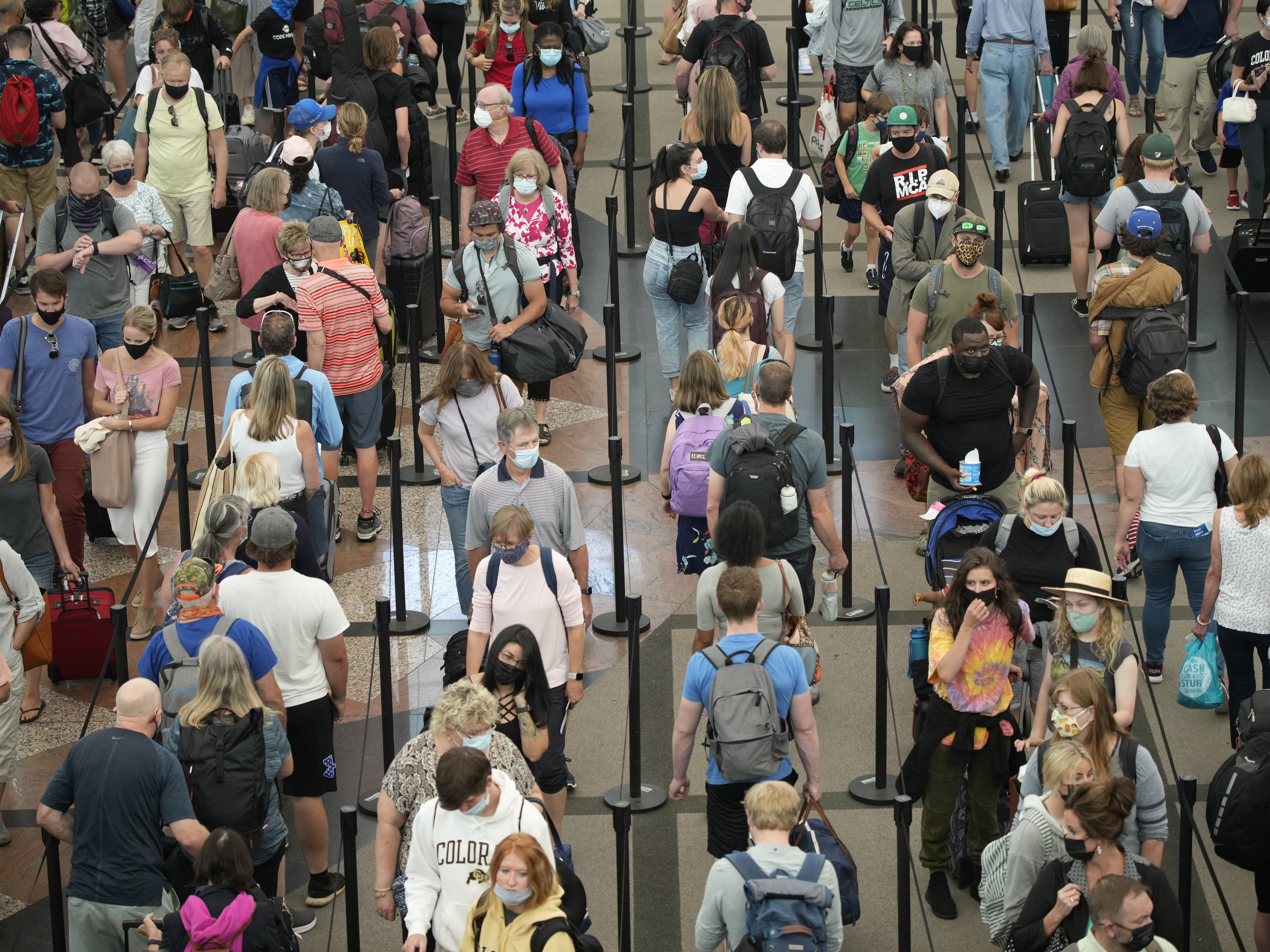 caption: In this June 16, 2021 file photo, travelers queue up in long lines to pass through the south security checkpoint in Denver International Airport in Denver.