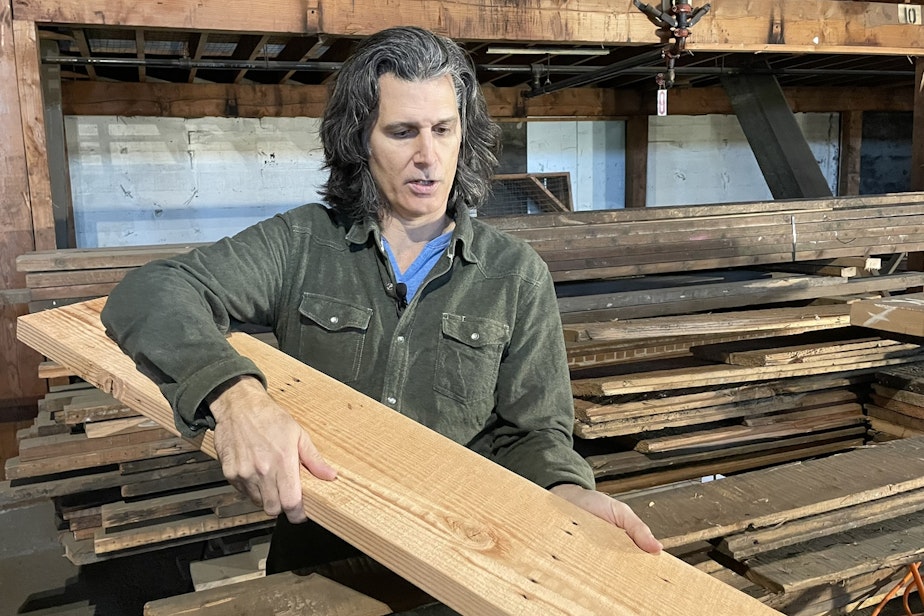 caption: Ben Pearson of the building "deconstruction" company Sledge shows off a slab re-milled from old Seattle lumber
