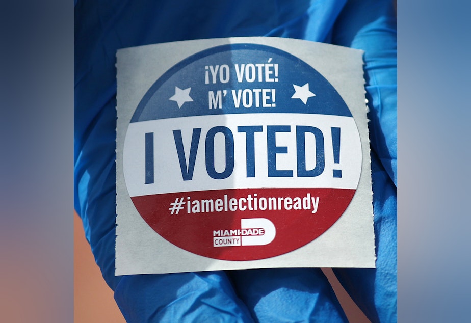 caption: A voter holds an, 'I Voted!' sticker, after casting her ballot during the Florida presidential primary last March.