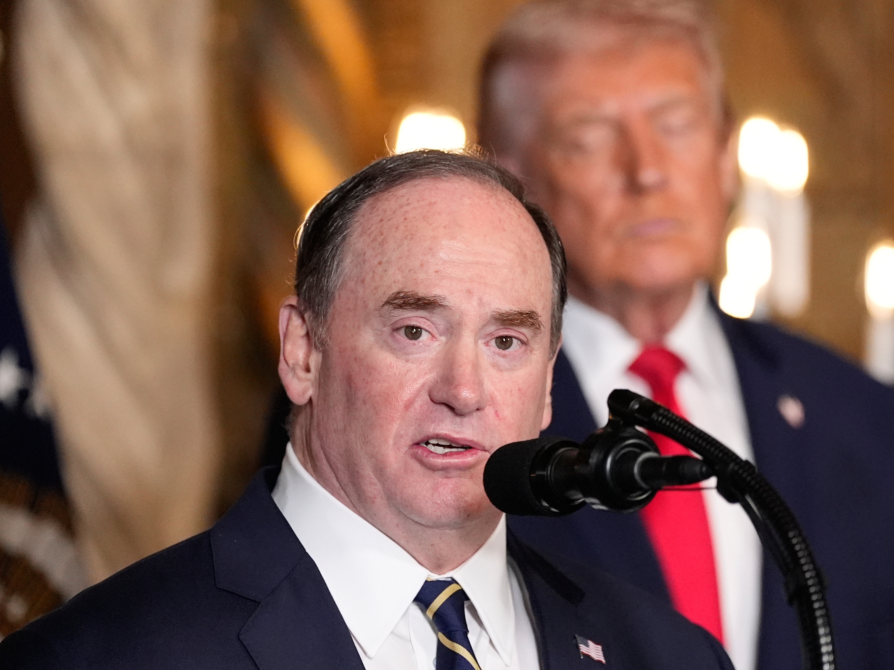 caption: Secretary of the Navy John Phelan speaks, as President Trump listens, at Trump's Mar-a-Lago club on Dec. 22 in Palm Beach, Fla.