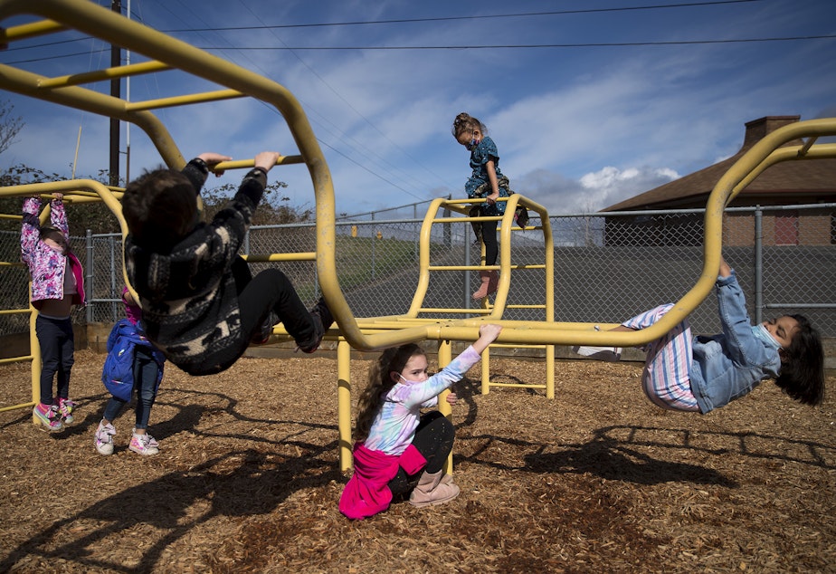 caption: Kindergarten students at Jackson Elementary play on a playground during recess on Tuesday, March 23, 2021, at the school along Federal Avenue in Everett. With hybrid learning, students have the option to attend in-person classes two days per week.