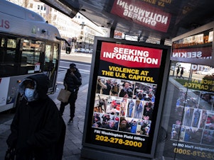 caption: At a bus stop on Pennsylvania Avenue Northwest in Washington, D.C., a notice from the FBI seeks information about people pictured during the riot at the U.S. Capitol on Wednesday.