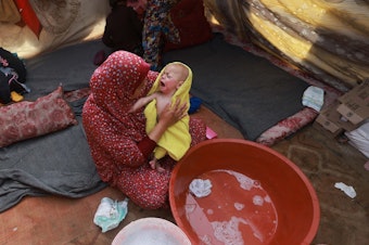 caption: A woman dries a baby in a towel after giving the infant a bath inside a tent at a camp for displaced Palestinians in Rafah, in southern Gaza, on Jan. 18.