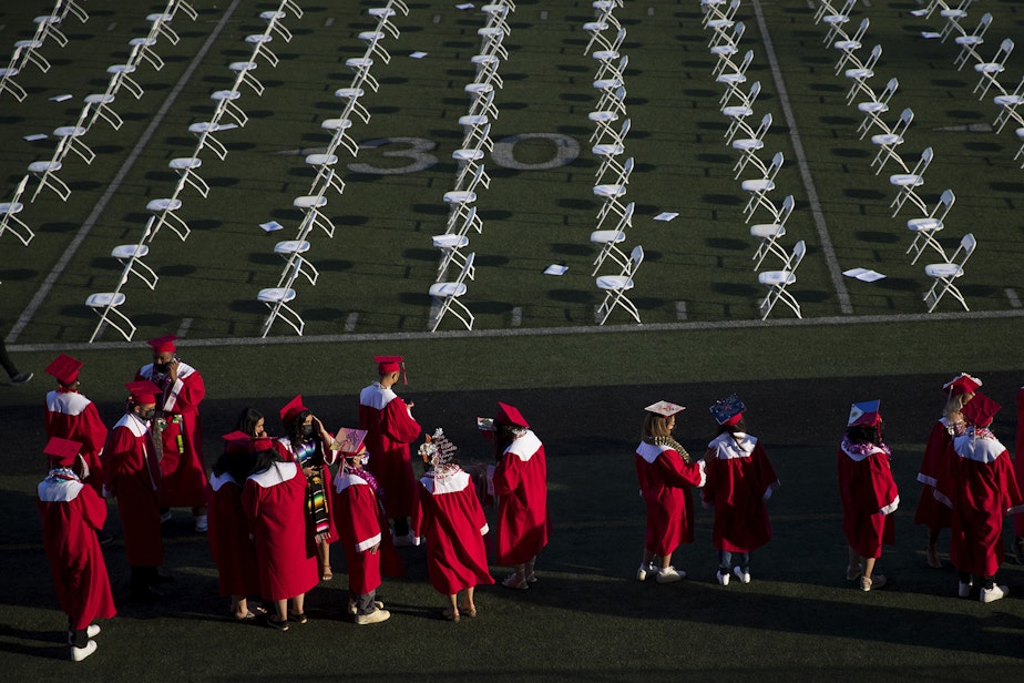 caption: Cleveland Stem High School seniors line up before taking their seats ahead of the in-person commencement ceremony on Tuesday, June 15, 2021, at Memorial Stadium in Seattle. 