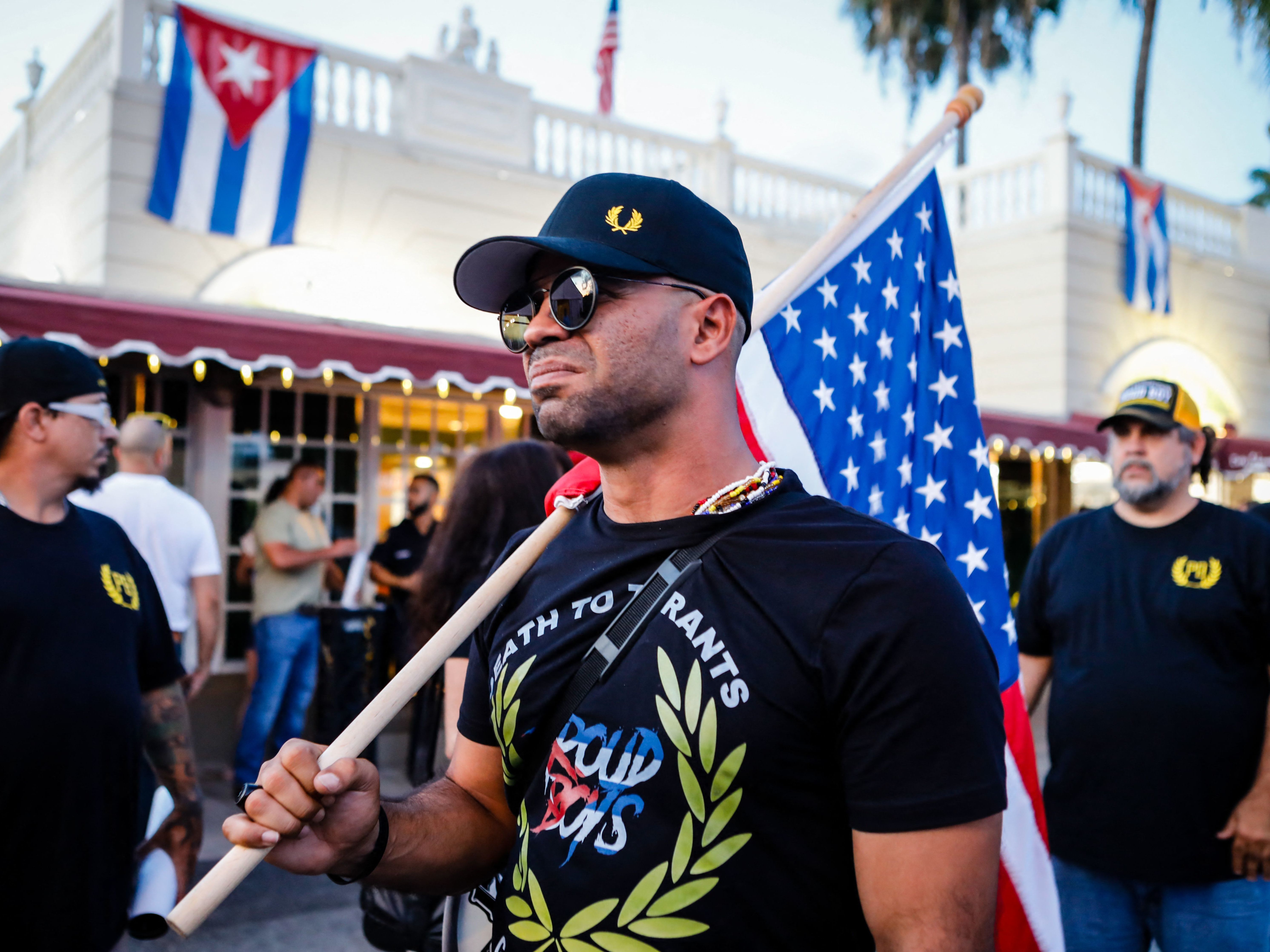 caption: Henry "Enrique" Tarrio, leader of the Proud Boys, holds a U.S. flag during a July protest in Miami as part of a show of solidarity for Cubans who were demonstrating against their government in Cuba.