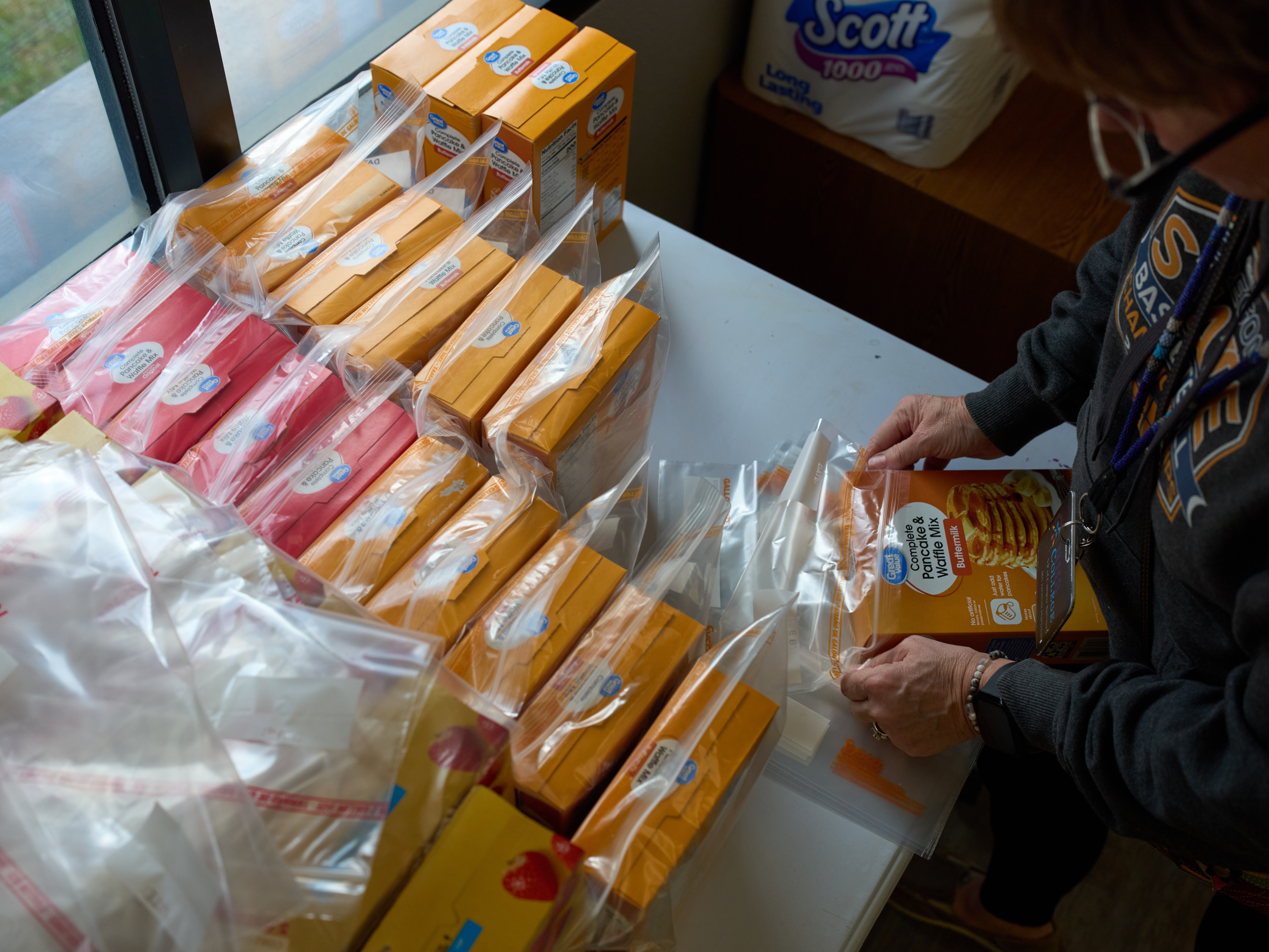 caption: Jen Janecek Hartman helps prepare bagged meals for a food bank for students at Nueta Hidatsa Sahnish College, Thursday, Oct. 30, 2025, in New Town, N.D.