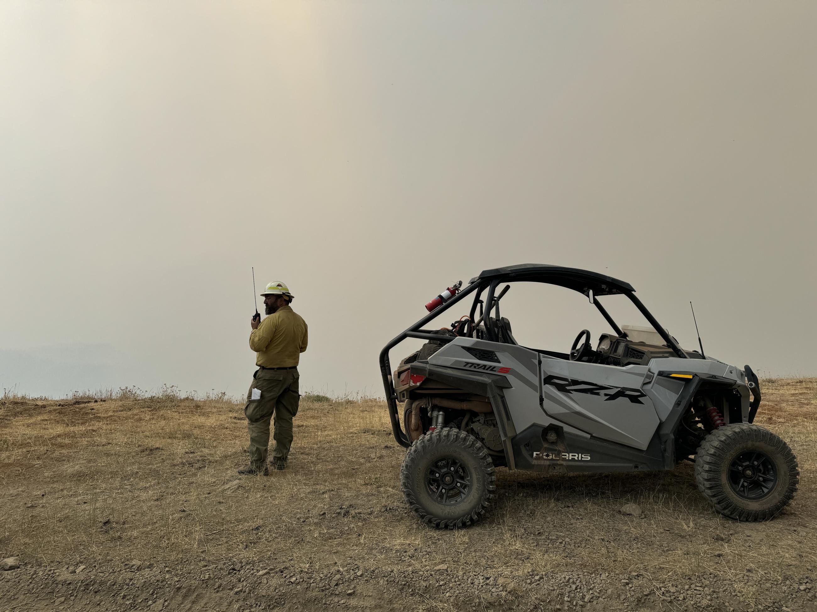 caption: A firefighter radios in while viewing smoke from Cougar Creek fire north of the Washington Oregon border in Asotin County.