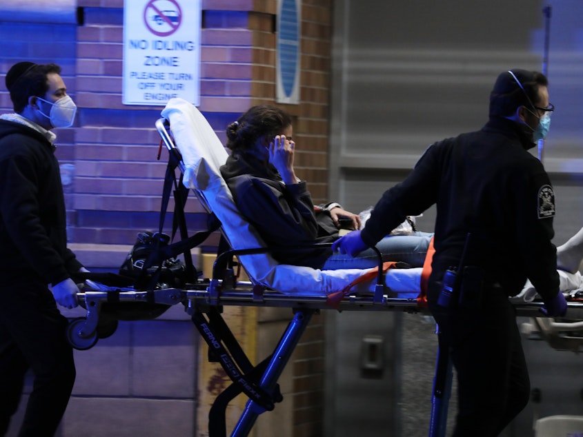 caption: Medical workers take in patients outside a coronavirus intake area at Maimonides Medical Center in Brooklyn, New York.