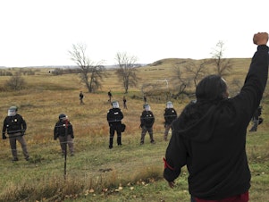 caption: A Dakota Access pipeline protester defies law enforcement officers who are trying to force them from a camp on private land in the path of pipeline construction, Thursday, Oct. 27, 2016 near Cannon Ball, N.D.