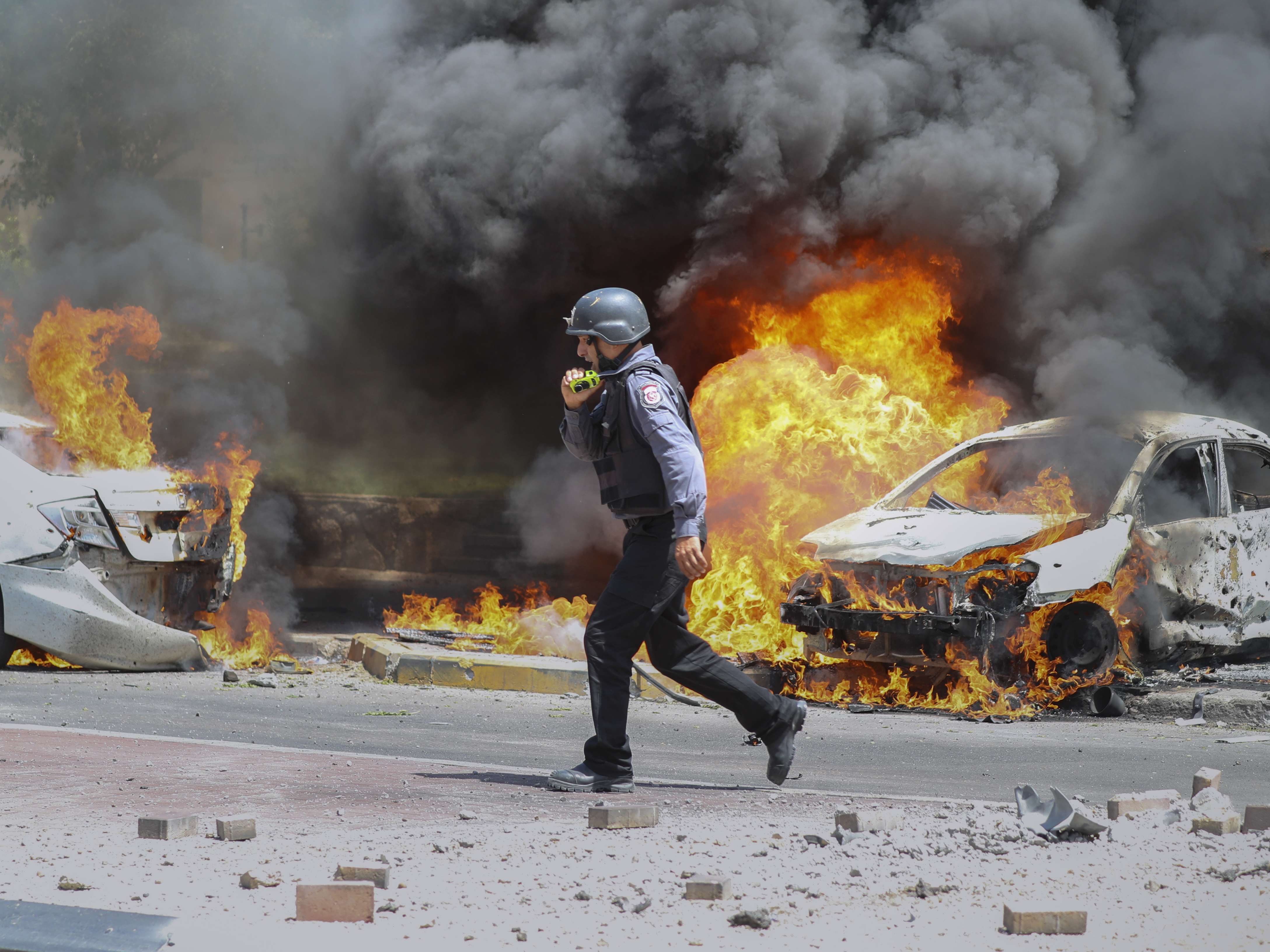caption: An Israeli firefighter walks next to cars hit by a rocket fired from Gaza on Tuesday in the southern Israeli city of Ashkelon.