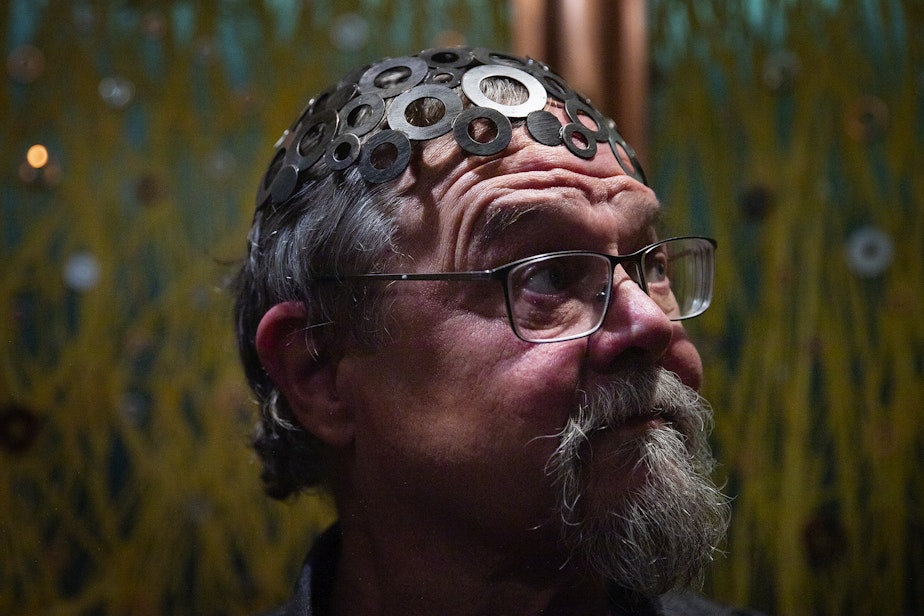 caption: Robert Rudine is shown wearing a hat that he calls the ‘brainwasher,’ aboard his houseboat, the self-declared sovereign nation of Tui Tui, on Tuesday, March 26, 2024, in Seattle. 