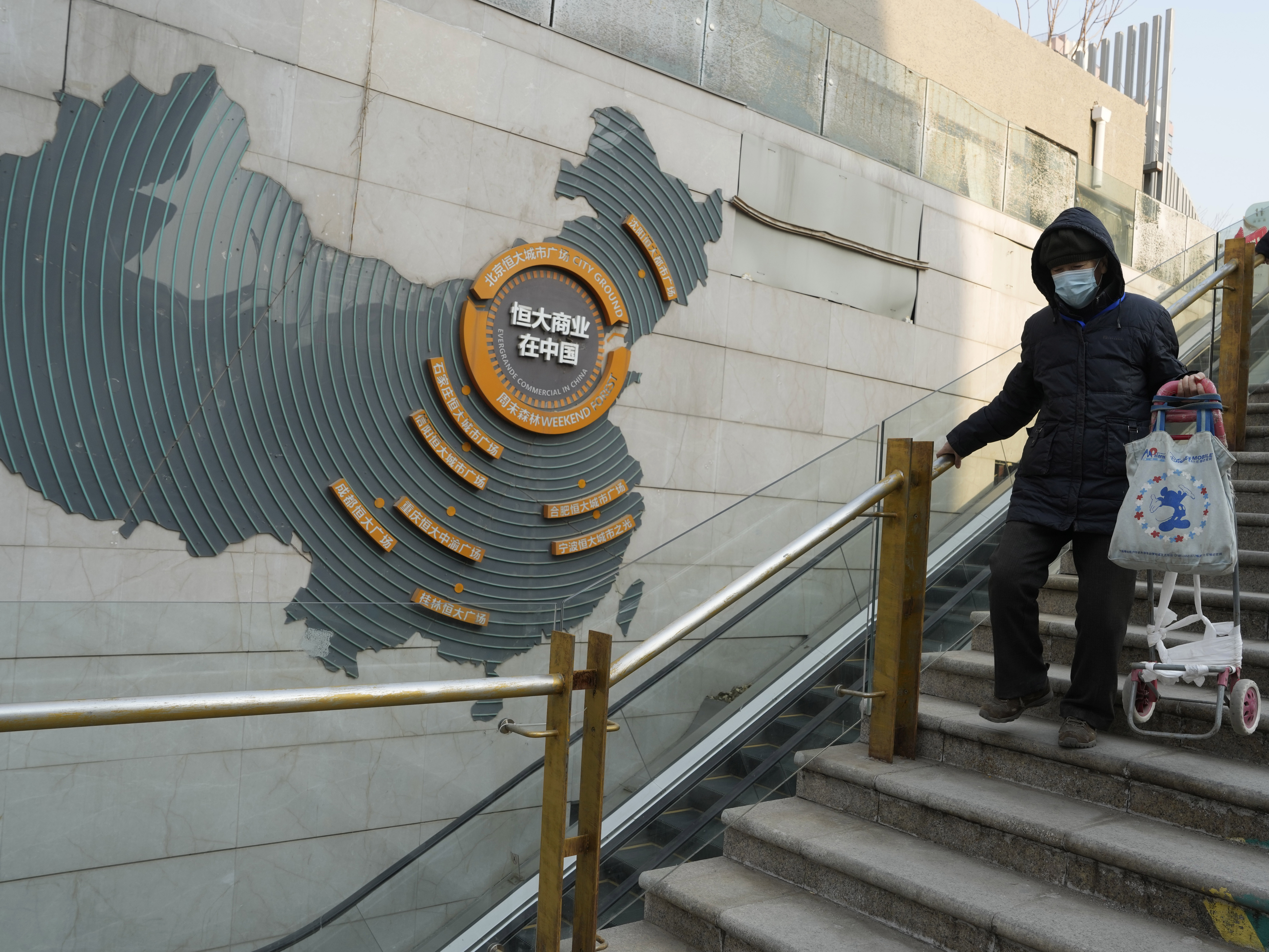 caption: Residents walk through a partially shuttered Evergrande commercial complex in Beijing, Monday, Jan. 29, 2024.