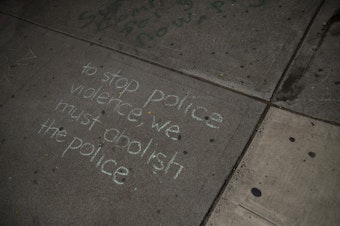 caption: 'To stop police violence, we must abolish the police,' reads chalk writing on a sidewalk at the intersection of 11th Avenue and East Pine Street on Tuesday, April 20, 2021, following the reading of the guilty verdict in the trial of Derek Chauvin for the murder of George Floyd, in Seattle. 